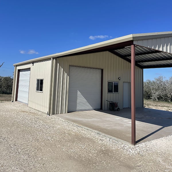 Metal storage building with large doors and an attached carport on a clear day in San Antonio, TX.