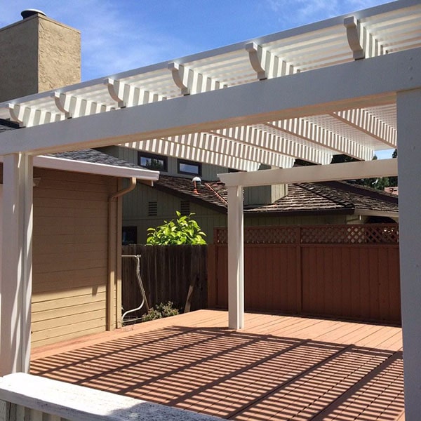 White pergola casting striped shadows on a wooden deck in a sunny backyard in San Antonio, TX.