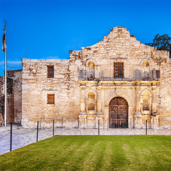 The Alamo mission on a sunny day, clear blue sky, with no people visible in San Antonio, TX.