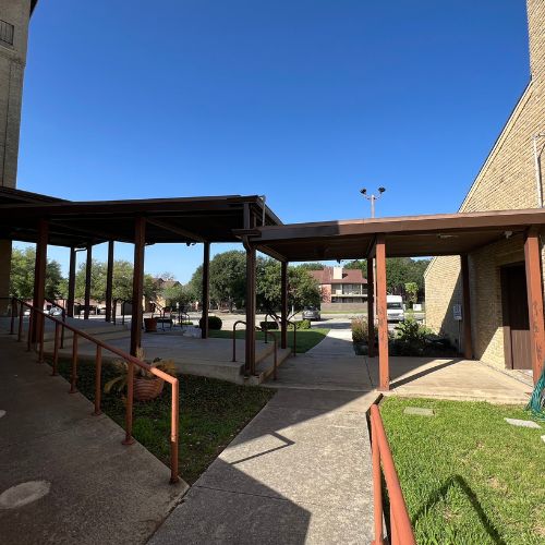 Covered walkway beside a building on a sunny day with a clear blue sky River City Gutters in Houston, TX.